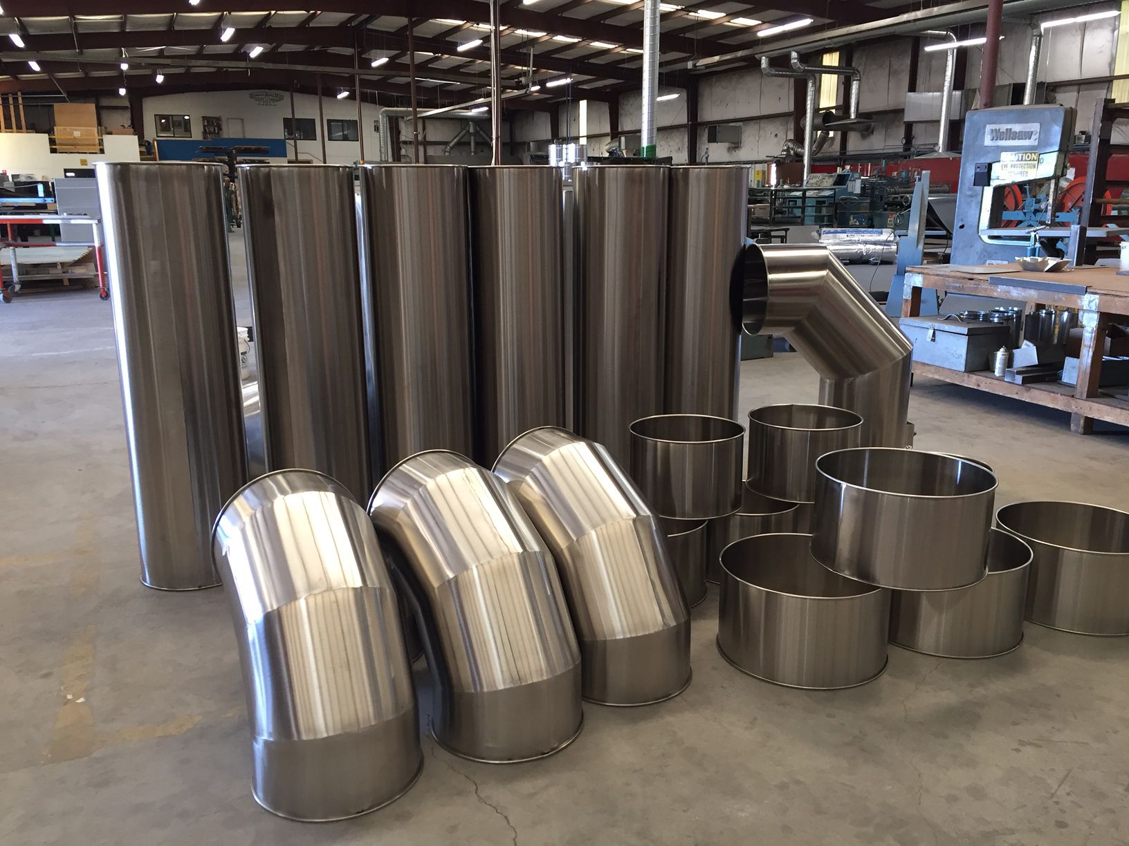 Stainless steel plus ductwork parts on display inside of a commercial warehouse.