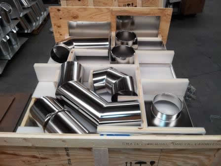 Various stainless steel ducting parts shown in a stock warehouse.